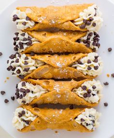 chocolate chip crepes with cream and chocolate chips on top are arranged on a white plate