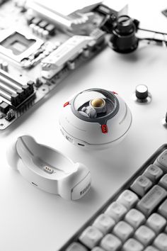 an electronic device sitting on top of a white table next to a keyboard and mouse