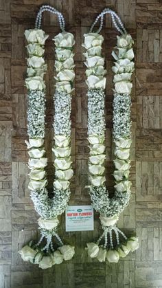 white flowers are arranged in the shape of two columns with pearls on them and beads hanging from each side