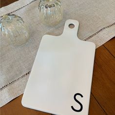 a white cutting board sitting on top of a table next to two glass vases