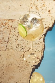 a close up of a wine glass on a table with water in the back ground