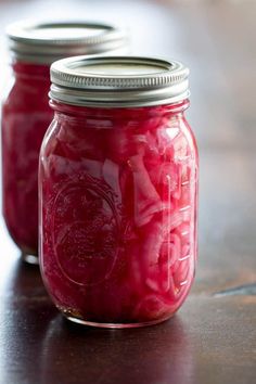 two jars filled with pickles sitting on top of a table