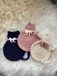 three crocheted items laying on top of a white furnishing floor next to each other