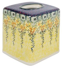 a yellow and black candle holder with flowers on it