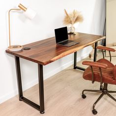 a wooden desk with a laptop on it in front of a chair and a lamp