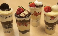 four dessert cups with strawberries and whipped cream on the top one is filled with chocolate