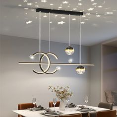 a dining room table and chairs with lights hanging from the ceiling