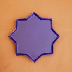 a purple plate sitting on top of a yellow tablecloth covered floor next to a brown wall