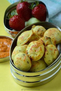 some food is in a metal bowl on a yellow table with strawberries and dip