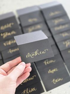 a person holding up a business card in front of some black and gold name tags