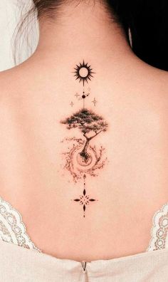 the back of a woman's neck with a tree and sun tattoo on it