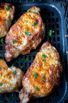 four pieces of chicken on a grill with parsley sprinkled on the side