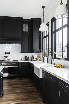 Modern black and white kitchen with pendant lights, dark cabinetry, white countertops, and stainless steel appliances. Black Kitchen Cabinets White Appliances, White Counters Black Cabinets, Black White Cabinets Kitchen, Black Trim Interior Kitchen, Black White House Decor, White Countertops Black Cabinets, White Kitchen Dark Walls, White Kitchen Black Cabinets, Kitchen Black Cabinets White Counter