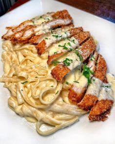 a white plate topped with pasta and meat covered in sauce