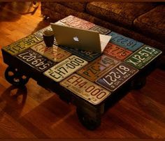 an apple laptop sitting on top of a coffee table with license plates all over it