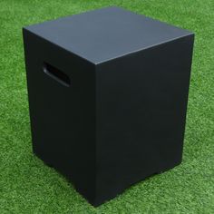 a black box sitting on top of a lush green field