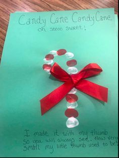 a piece of paper with a red ribbon on it and candy cane candy cane card