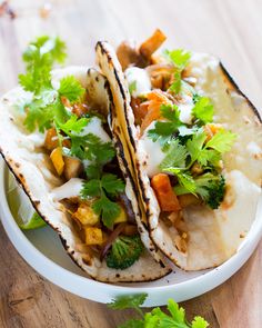 two tacos on a plate with cilantro and carrots