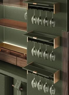 a green cabinet with wine glasses hanging from it's sides