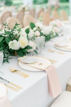 the table is set with white and gold place settings, napkins, and flowers