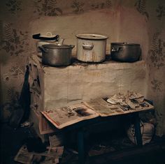 an old kitchen with pots and pans sitting on top of a table next to a newspaper