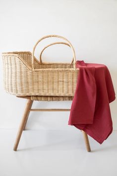 a wicker baby crib with a red blanket on it's side and a white wall in the background