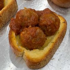 some meatballs are in a bread bowl on a piece of tin foil with other food items around it