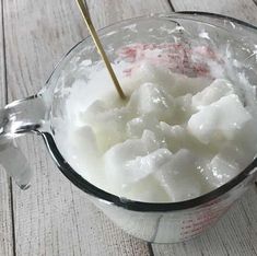 a blender filled with ice cubes on top of a wooden table next to a measuring cup