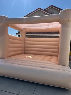 an inflatable bed sitting on top of a sidewalk next to a house and blue sky