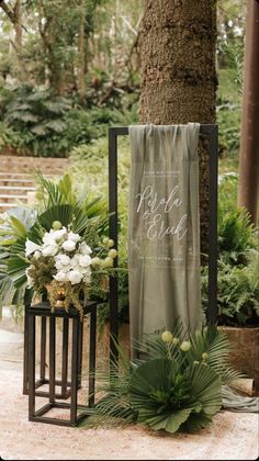 an outdoor ceremony area with greenery and flowers on the ground, next to a tree