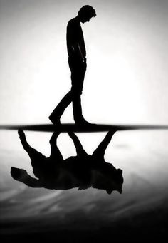 a man walking across a body of water with his reflection in the water behind him