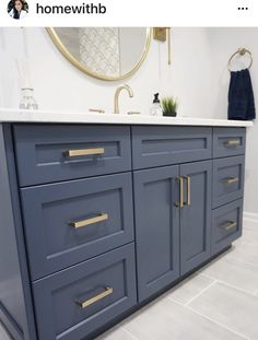 the bathroom vanity is painted blue and has gold pulls on it's drawers, which also have brass handles