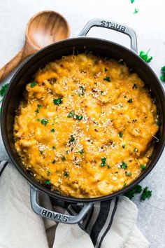 a pot filled with macaroni and cheese on top of a white tablecloth