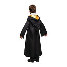 a little boy dressed in a black and gold graduation gown, standing with his hands on his hips