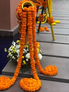 orange and white flowers are arranged on the ground next to two yellow poles with handles