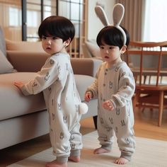 two young children standing next to each other in bunny onesuits on the floor