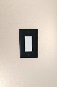 a black and white light switch on a wall in a room with no one around it