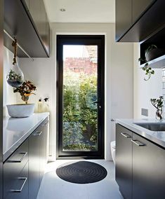 a bathroom with a black door and white counter top next to a sink, toilet and window