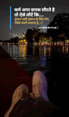 someone is sitting on the edge of a boat at night with their feet in the water