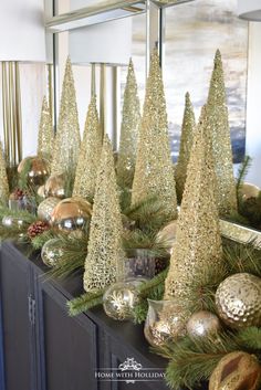 gold christmas trees are sitting on top of a dresser