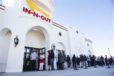 people are lined up in front of an in - n - out store