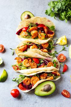 shrimp tacos with avocado, tomatoes and cilantro on the side