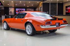 an orange car is parked in a showroom