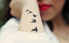 a woman is holding her arm with birds on it and the words in spanish are written below