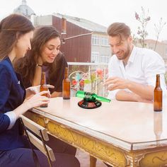 three people sitting at a table with beer