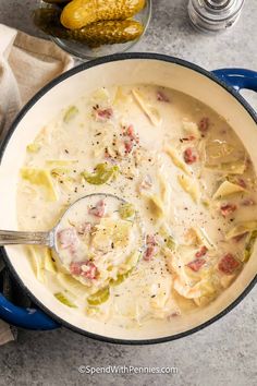 a pot filled with pasta and meat soup on top of a table next to some bread