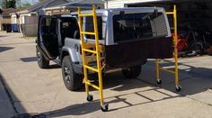 a jeep with a ladder attached to it parked in front of a garage