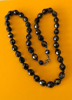 This classic nice quality 18 inch 7mm faceted jet black bead necklace is a classic closet basic. The faceted beads have seed bead spacers and wire strung smaller beads near the clasp to keep the back from being bulky. The necklace is sturdy with a gold tone lobster claw closure. The necklace is a classic inches long. This necklace is a great closet basic in wonderful vintage condition. The beads have a bright carnival sheen. I specialize in finding fun wearable vintage jewelry. Please browse my Classic Black Beaded Necklaces, Black Necklace With Oval Spacer Beads, Black Faceted Round Beaded Necklaces, Black Faceted Beaded Necklaces, Black Jewelry With Faceted Oval Beads, Black Jewelry With Oval Faceted Beads, Classic Faceted Round Bead Necklaces, Formal Beaded Necklaces With Faceted Beads, Formal Faceted Beaded Necklaces