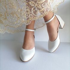 a woman wearing white shoes with lace on the bottom and heels at the ankle length