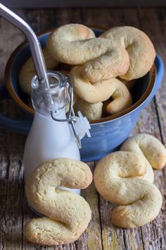 a blue bowl filled with cookies next to a bottle of milk